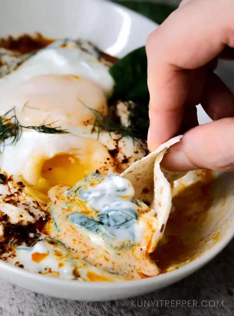Dipping Turkish poached egg spinach with flatbread.