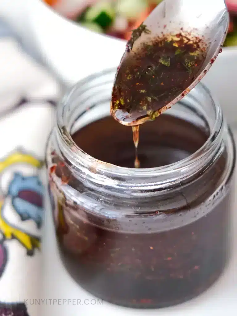 Zoomed in of spooning Sumac Dressing from the glass jar