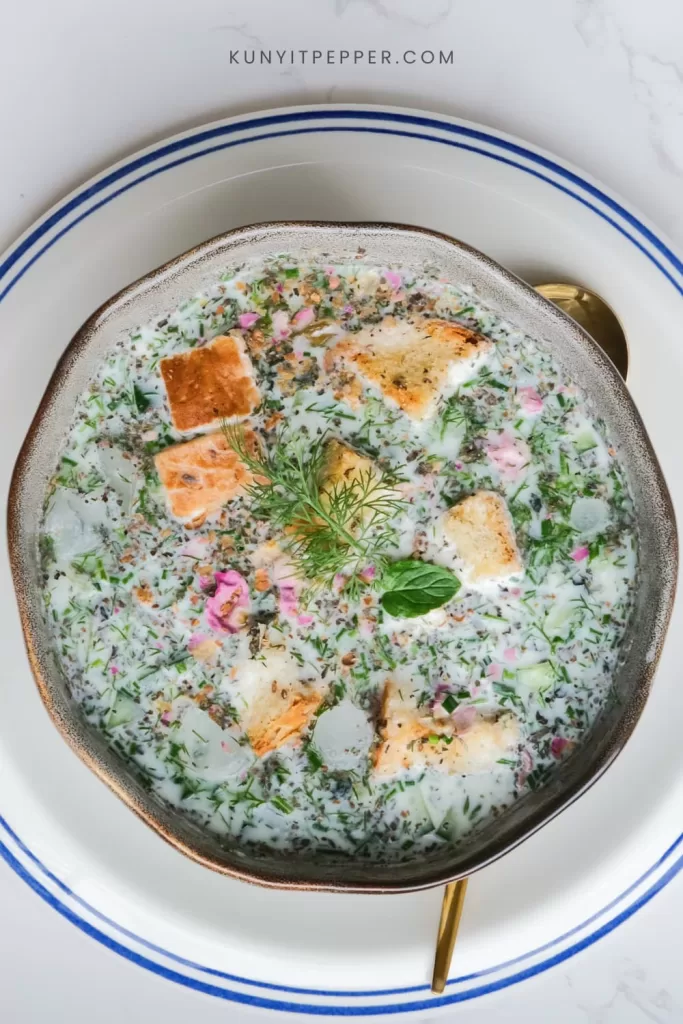 Persian cold yogurt soup with cucumber and fresh herb topped with bread
