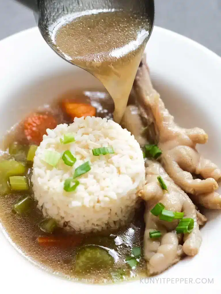 Pouring a scoop of brothy chicken feet soup on rice garnished with scallions