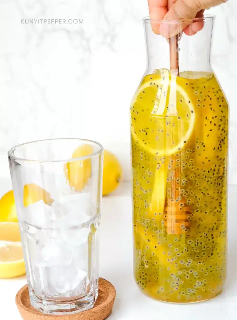 Stirring honey in basil seed drink with honey dipper.
