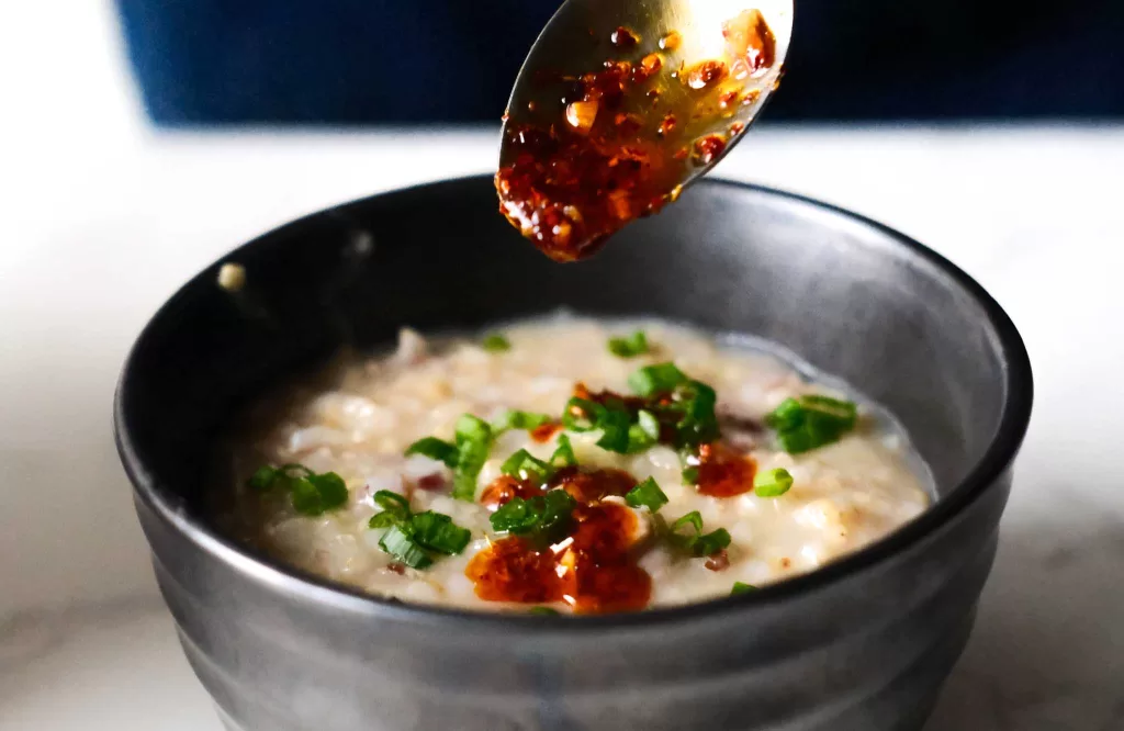 Drizzle chili oil on congee top with scallion in a bowl