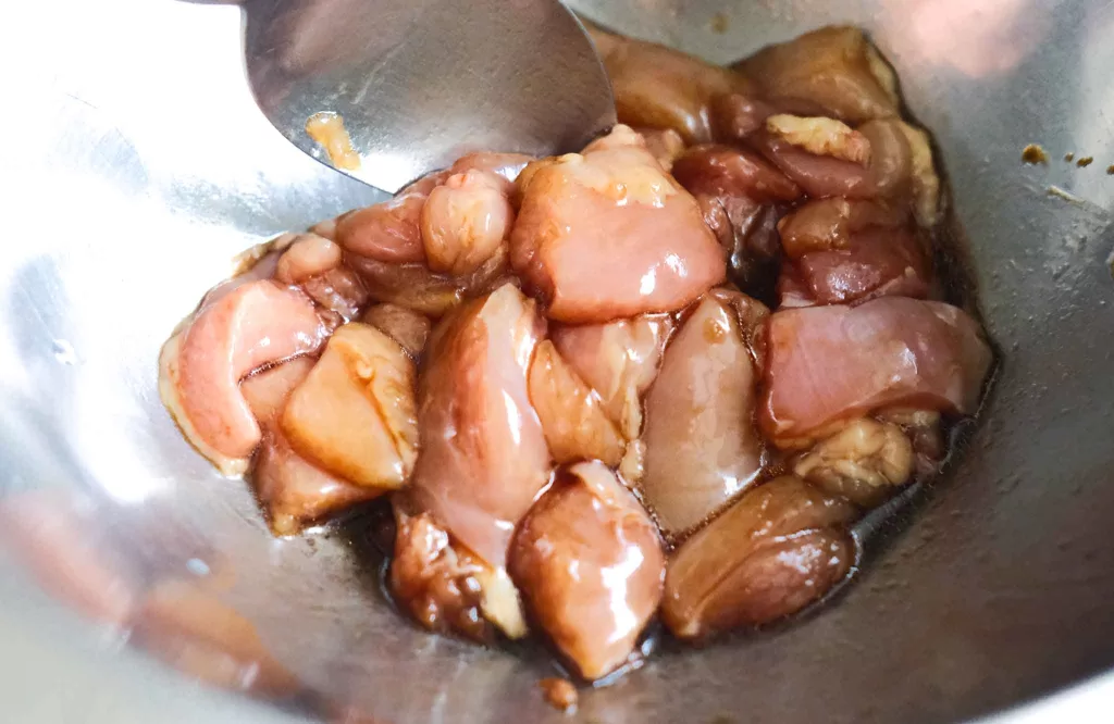 Mixing chicken with soy soy and sesame with a spoon in a bowl