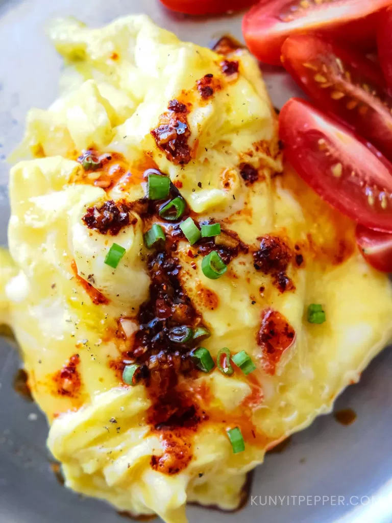 Top view of mmelete drizzled in garlic chili olive oil and garnished with scallion with a little baby tomatoes on the side