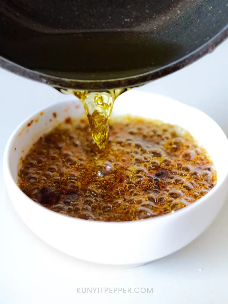 Pouring the remaining hot olive oil into chili flakes and garlic