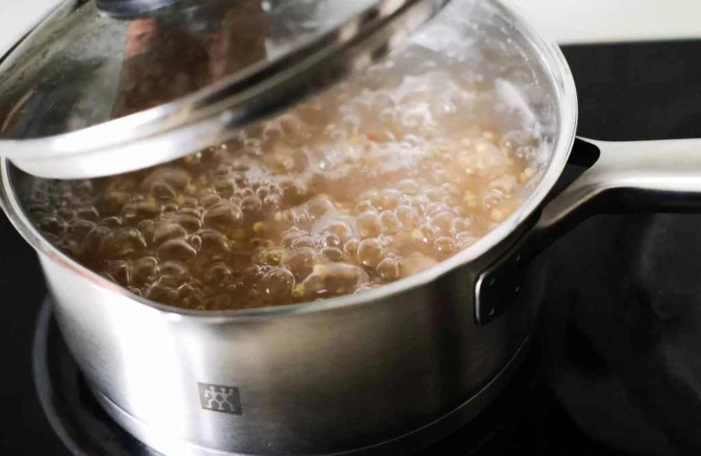 Simmering multigrain rice porridge in a pot on the stovetop with lid half opened