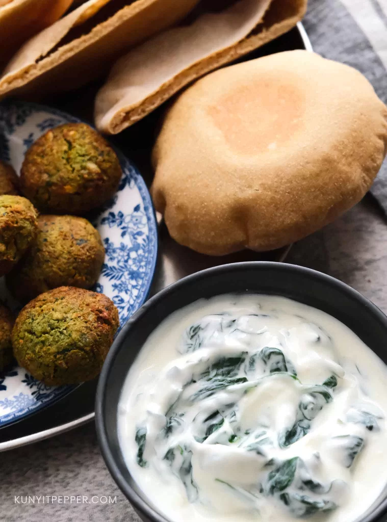 Spinach Yogurt Sauce Next to Falafel and Wholewheat Pita Bread.