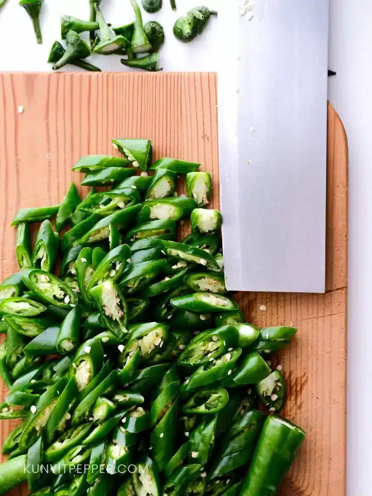 Sliced Green Chilli for pickling in a cutting board next to a knife